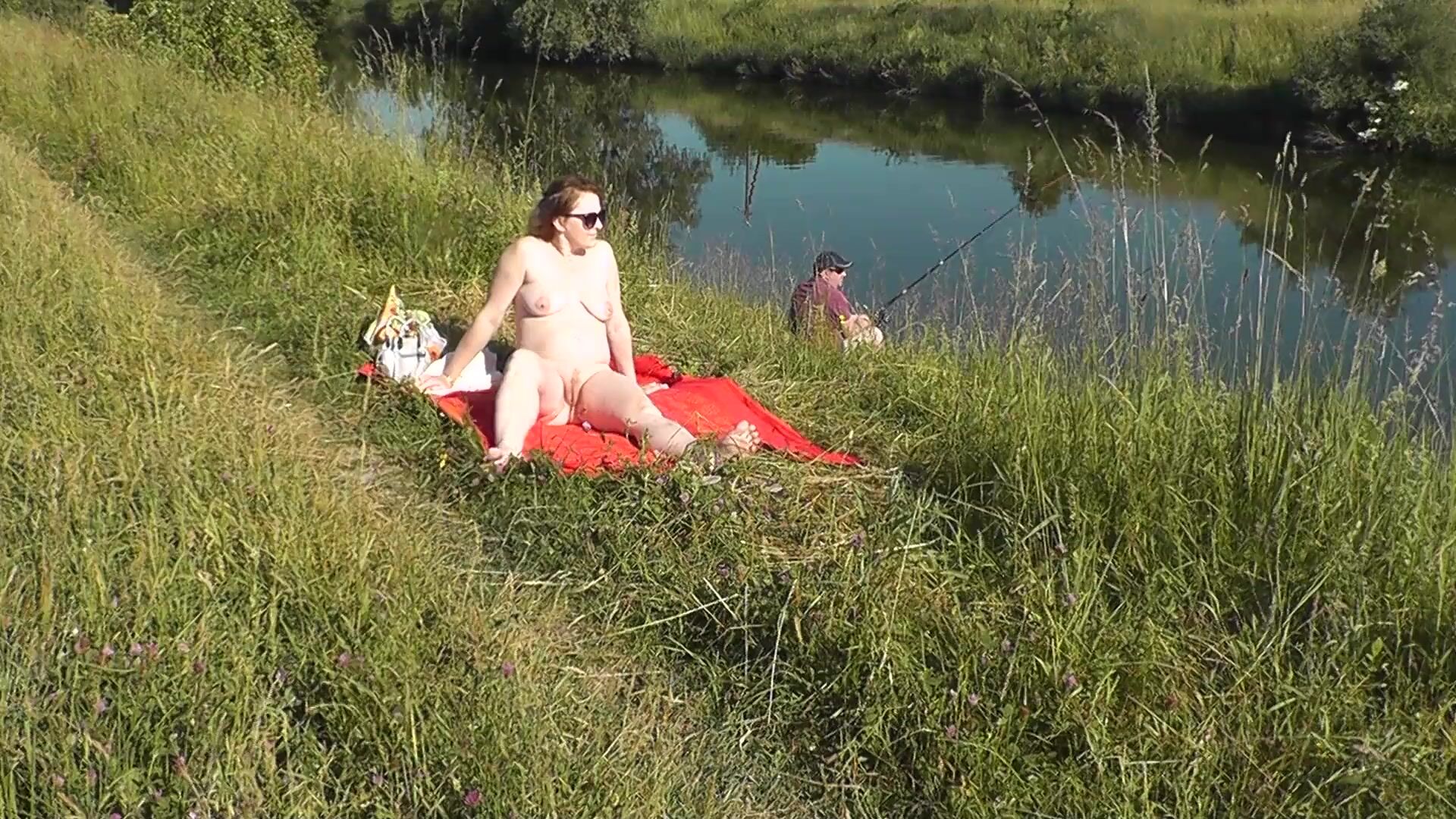 MILF sexy Frina na margem do rio despida e a apanhar banhos de sol nua. Um pescador aleatório observa-a, e no final decide juntar-se à mulher nua